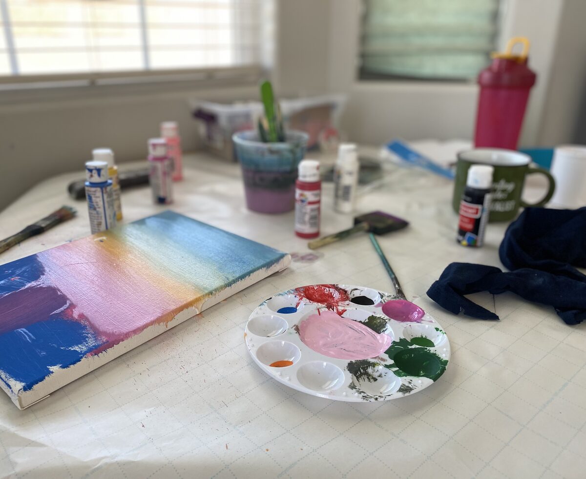 A sunset-colored painting on canvas next to a paint palette