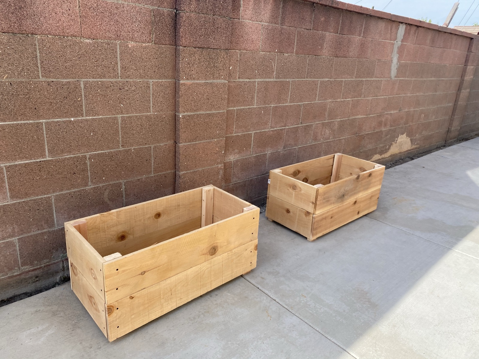 Two finished cedar planter boxes against a wall