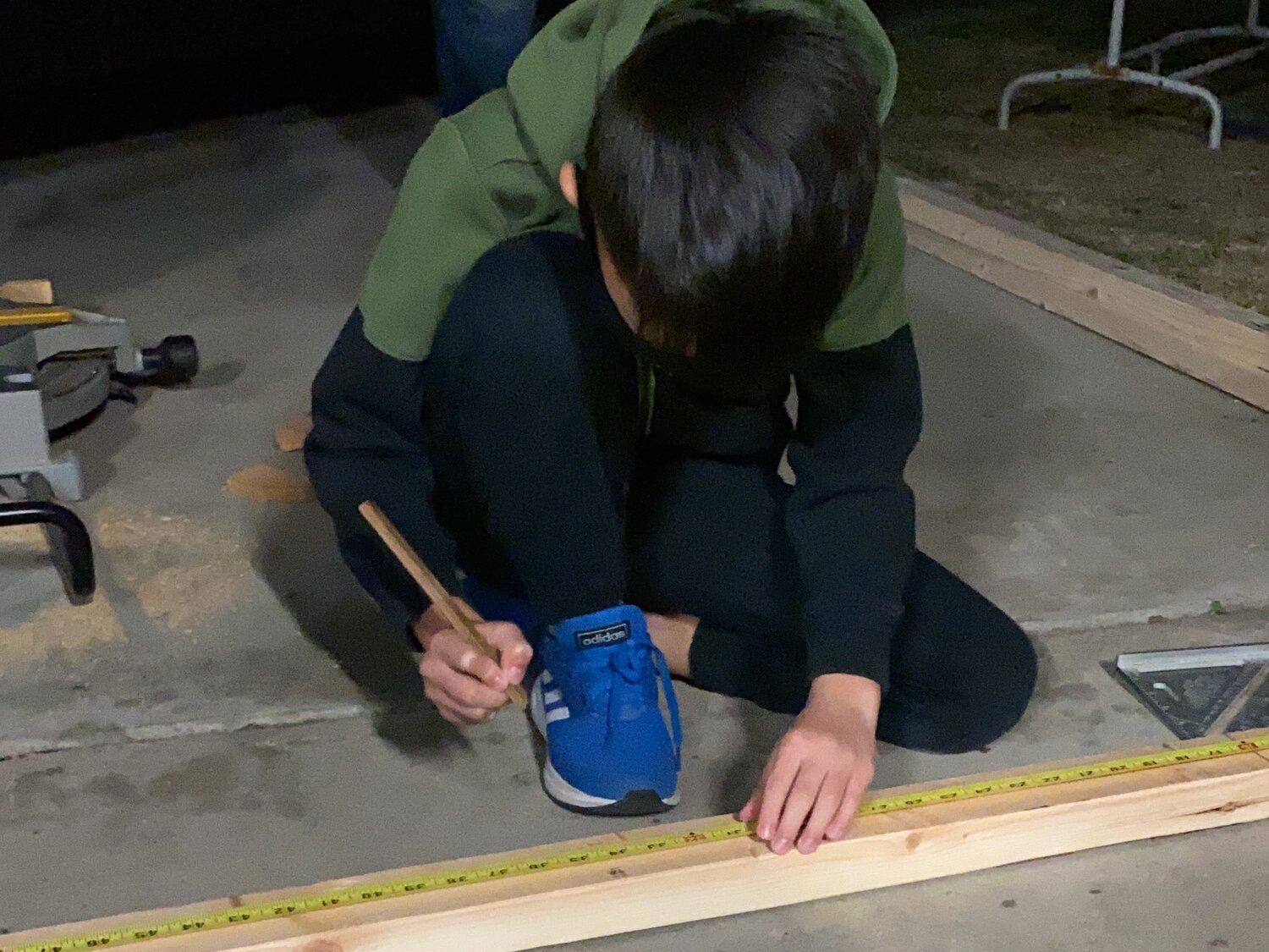 His son marking a cedar board with a pencil and tape measure